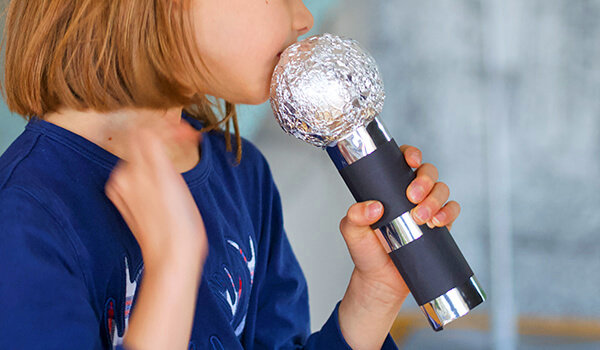 Kind singt mit selbstgebastelten Mikrofon